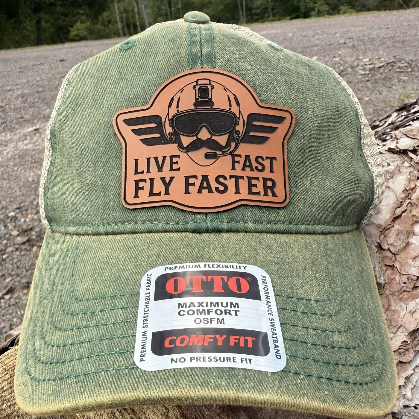 The Live Fast Fly Faster leather patch on a washed green trucker hat