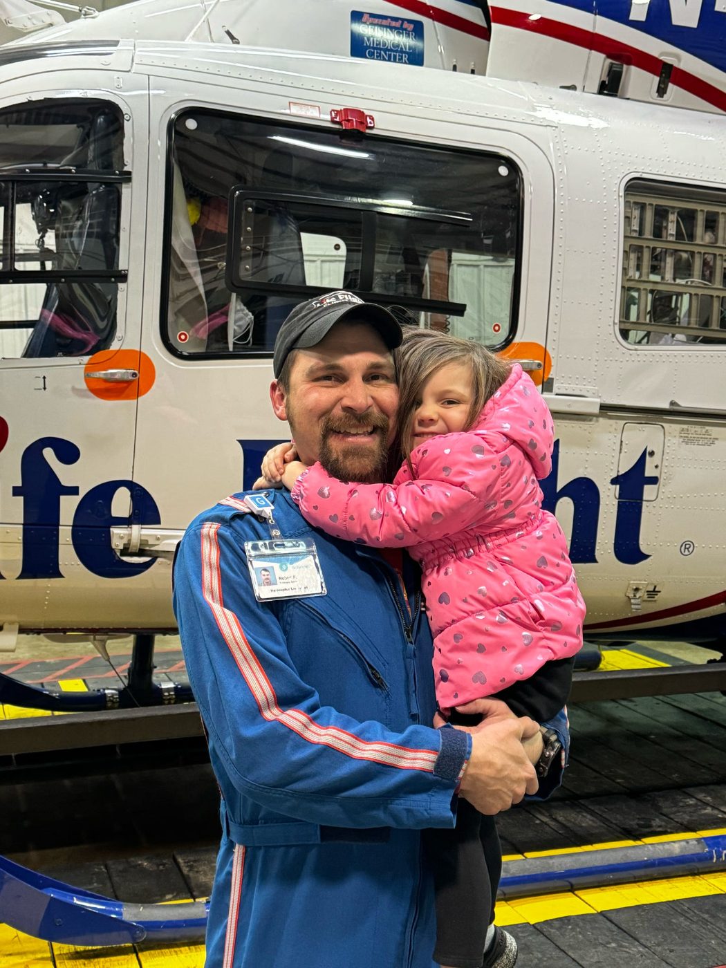 Rob holding his daughter in front of the Life Flight helicopter